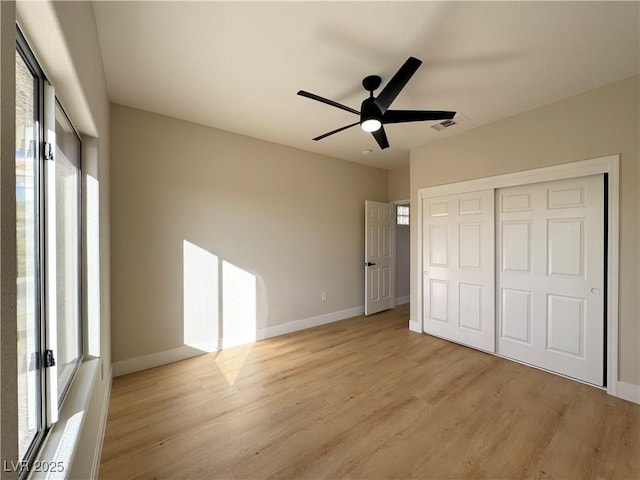 unfurnished bedroom with multiple windows, baseboards, visible vents, and light wood finished floors