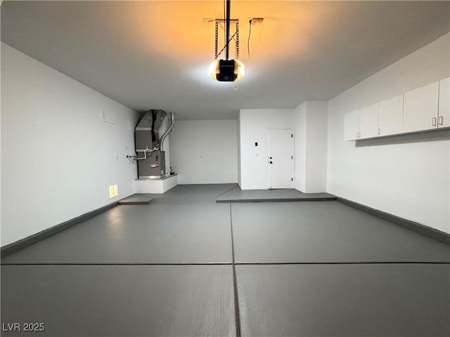 garage with heating unit, a garage door opener, and baseboards