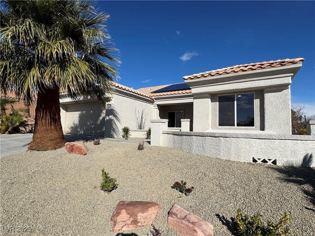 view of front of home featuring solar panels, a tile roof, and stucco siding