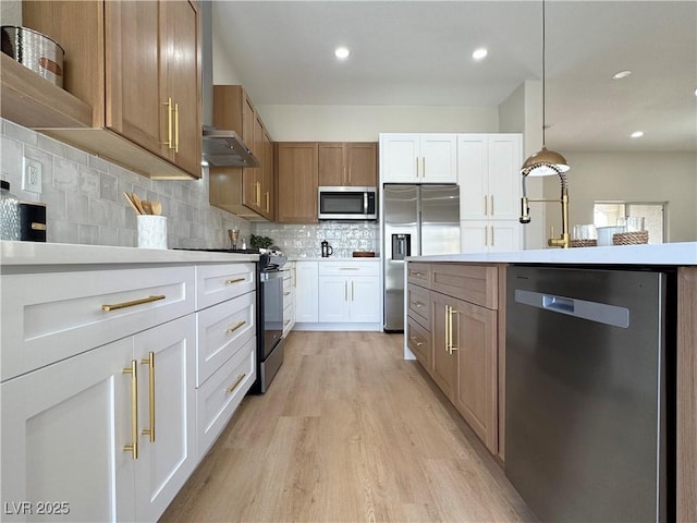 kitchen featuring light wood-type flooring, under cabinet range hood, appliances with stainless steel finishes, light countertops, and decorative backsplash