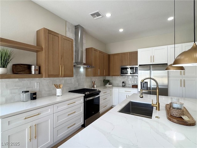 kitchen with visible vents, open shelves, a sink, appliances with stainless steel finishes, and wall chimney range hood