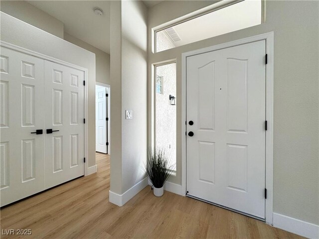 foyer with visible vents, baseboards, and light wood-style flooring