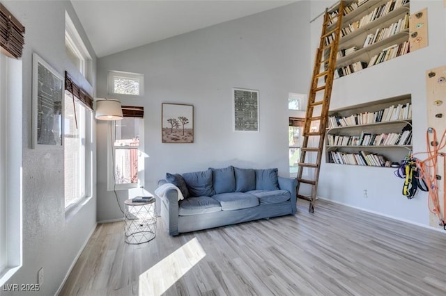 living area with baseboards, high vaulted ceiling, and wood finished floors