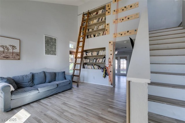 living room with stairs, a high ceiling, wood finished floors, and french doors