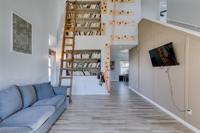 living area with wood finished floors, a towering ceiling, and baseboards