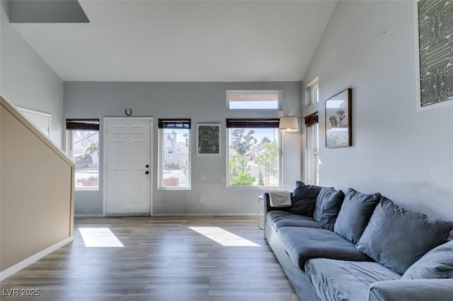 living area featuring high vaulted ceiling, baseboards, and wood finished floors