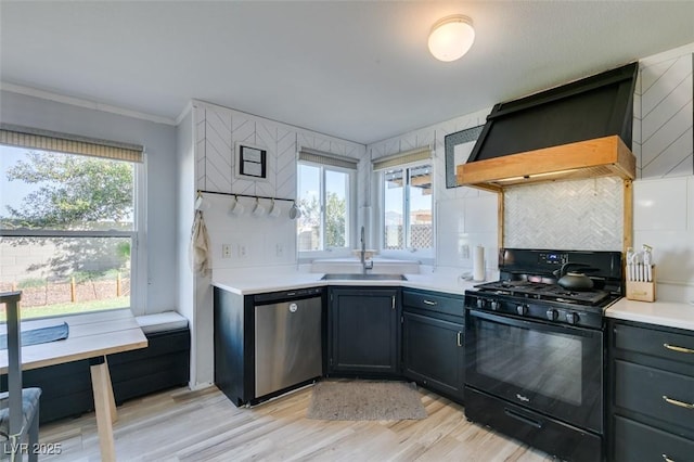 kitchen with black range with gas cooktop, a sink, light countertops, dishwasher, and custom range hood