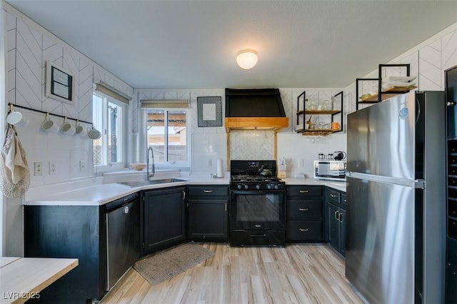 kitchen with black range with gas cooktop, dishwashing machine, custom range hood, freestanding refrigerator, and a sink