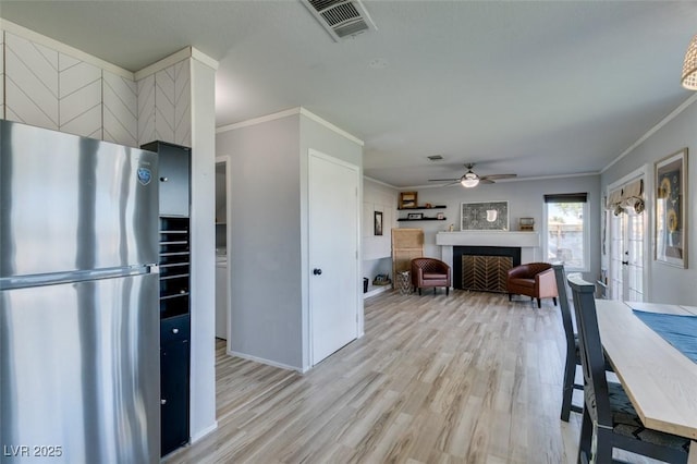 kitchen with visible vents, a fireplace, freestanding refrigerator, and light wood-style floors