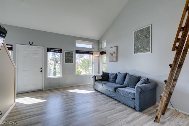 living room featuring light wood-type flooring, baseboards, and high vaulted ceiling