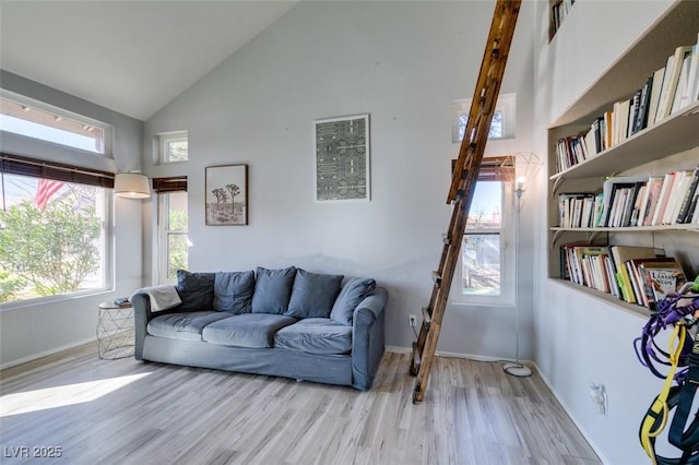 living area with baseboards, high vaulted ceiling, and wood finished floors