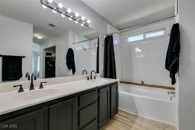 full bathroom with shower / bath combination with curtain, visible vents, a sink, and wood finished floors