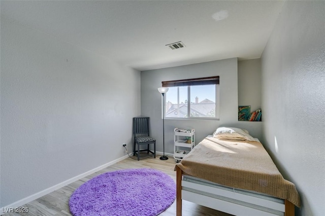 bedroom featuring visible vents, baseboards, and wood finished floors