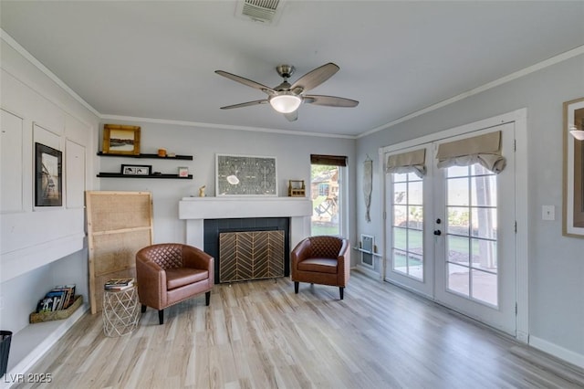 sitting room with french doors, wood finished floors, visible vents, and crown molding