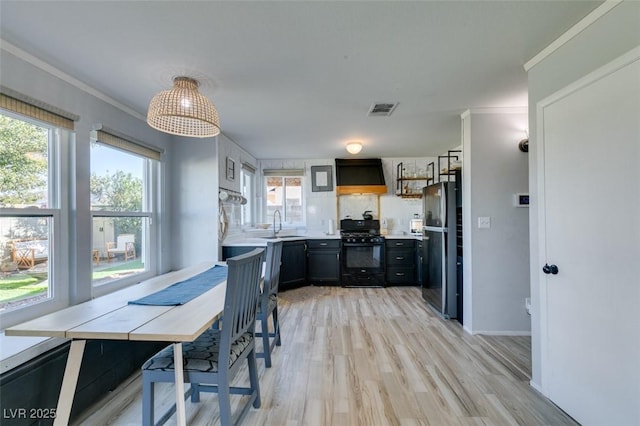 kitchen featuring black appliances, custom range hood, visible vents, and ornamental molding