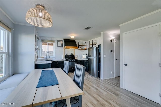 dining room featuring ornamental molding, light wood-type flooring, and visible vents