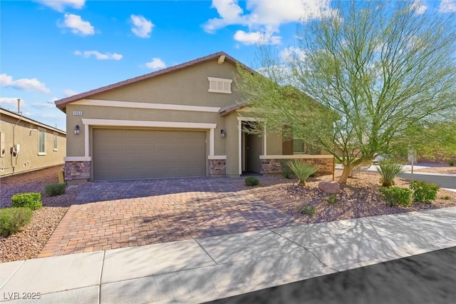 view of front of home featuring decorative driveway, stone siding, an attached garage, and stucco siding