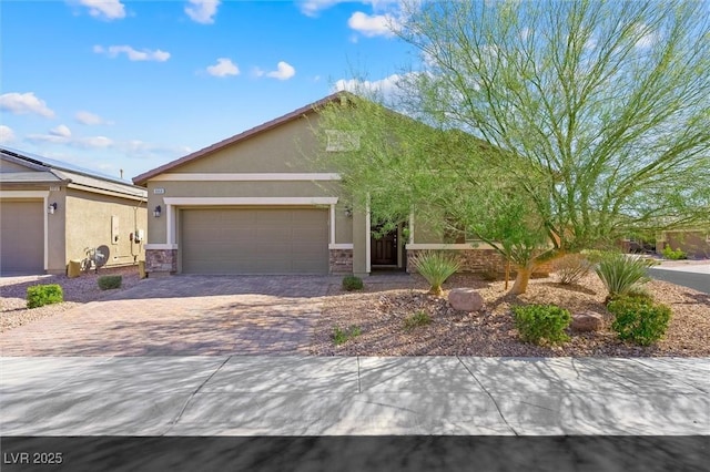 view of front of home with a garage, stone siding, decorative driveway, and stucco siding