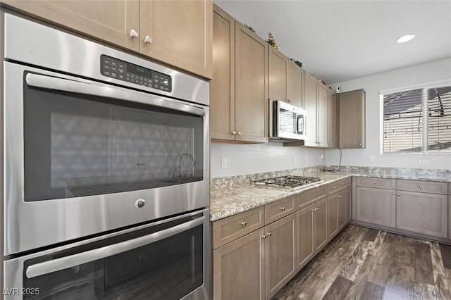 kitchen featuring light stone countertops, stainless steel appliances, dark wood-type flooring, and recessed lighting