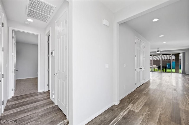 hallway featuring baseboards, visible vents, wood finished floors, and recessed lighting