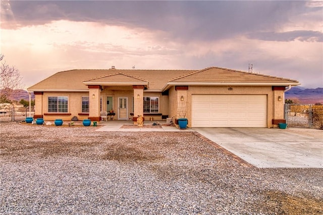 view of front of house featuring driveway, an attached garage, fence, and stucco siding