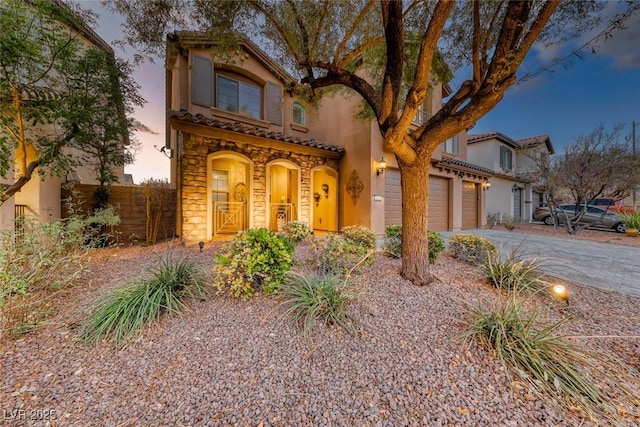 mediterranean / spanish home with driveway, stone siding, a tile roof, and stucco siding