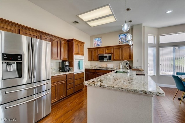 9816 Gerald Ct, Las Vegas, NV 89134 - kitchen with stainless steel appliances, a peninsula, brown cabinets, and wood finished floors