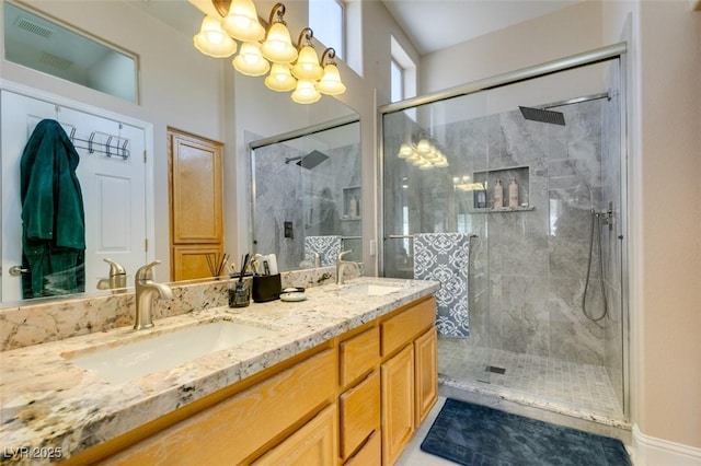 bathroom featuring double vanity, a stall shower, a sink, and an inviting chandelier