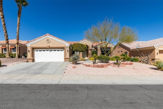 mediterranean / spanish home with a garage, a tile roof, driveway, and stucco siding