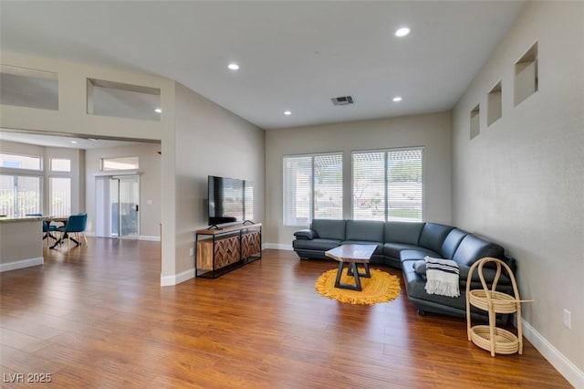 living area with recessed lighting, visible vents, baseboards, and wood finished floors