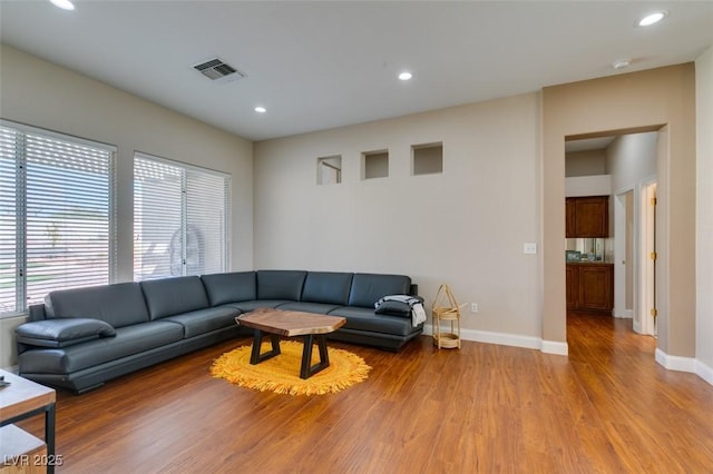 living room featuring baseboards, visible vents, wood finished floors, and recessed lighting