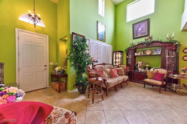 living area with a towering ceiling, an inviting chandelier, and tile patterned flooring