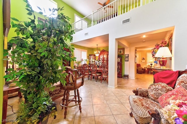 tiled living area featuring a towering ceiling, visible vents, and baseboards