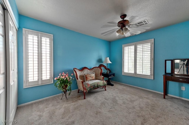 sitting room with a ceiling fan, carpet, and a healthy amount of sunlight