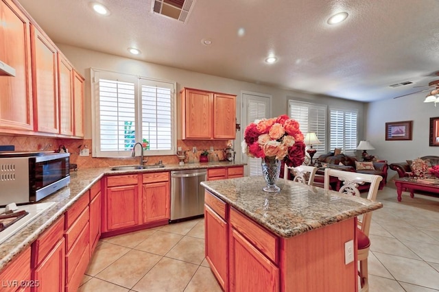 kitchen featuring open floor plan, appliances with stainless steel finishes, light tile patterned floors, and a sink