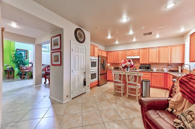 kitchen featuring stainless steel refrigerator with ice dispenser, visible vents, double oven, light tile patterned flooring, and a sink