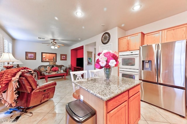 kitchen with light tile patterned floors, stainless steel fridge, visible vents, and white double oven