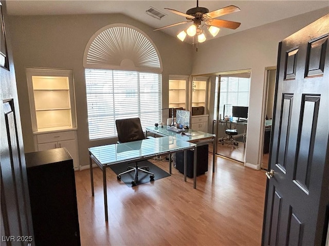 office space featuring built in shelves, lofted ceiling, visible vents, ceiling fan, and wood finished floors