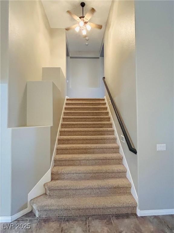 stairs featuring a ceiling fan and baseboards