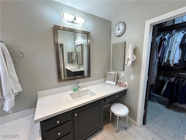 bathroom featuring a spacious closet, vanity, and baseboards