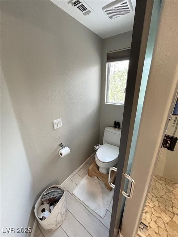 bathroom with baseboards, visible vents, a shower stall, and toilet