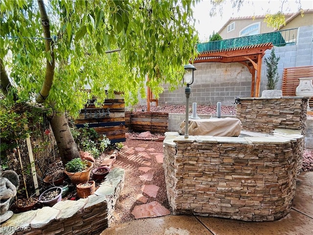 view of patio featuring a fire pit, exterior kitchen, fence, and a pergola