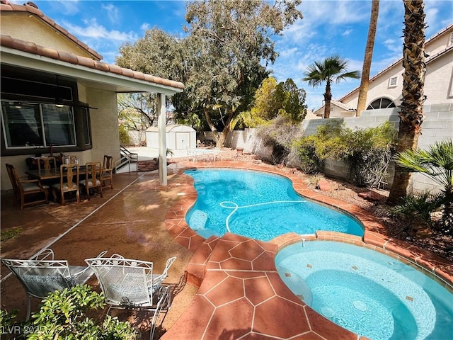 view of pool with a pool with connected hot tub, an outbuilding, a shed, a fenced backyard, and a patio