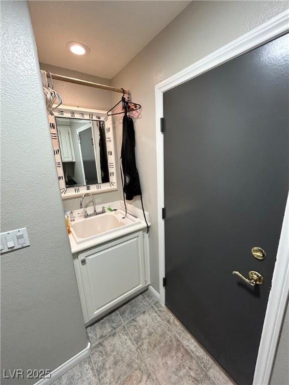 bathroom with vanity, a textured wall, and baseboards