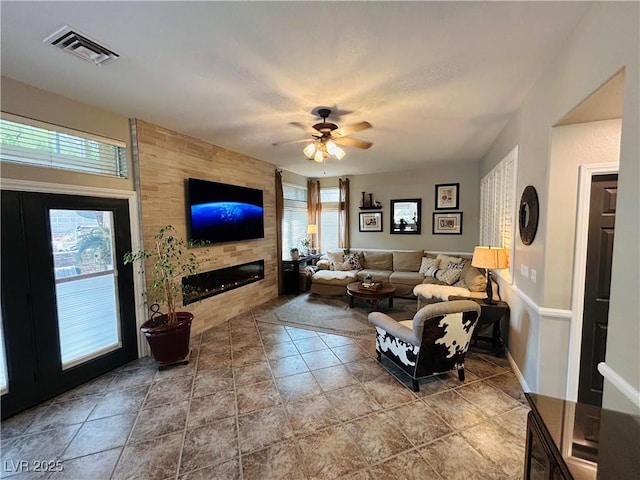 living room with a ceiling fan, a fireplace, visible vents, and a healthy amount of sunlight