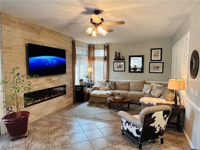 living room featuring tile patterned floors, ceiling fan, baseboards, and a tile fireplace