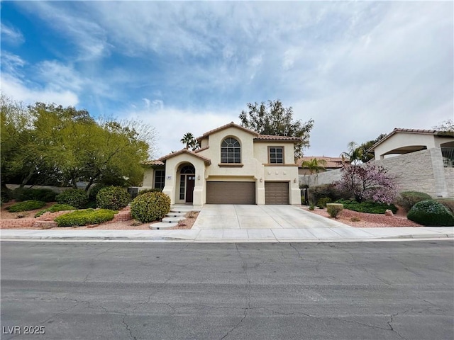 mediterranean / spanish-style house featuring a garage, stucco siding, a tiled roof, and concrete driveway