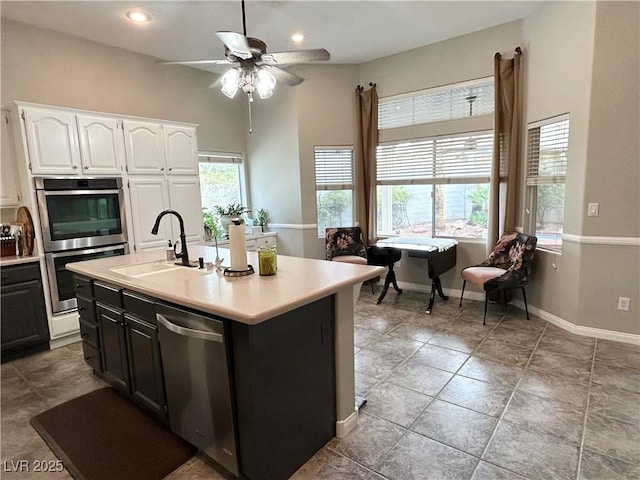 kitchen featuring stainless steel appliances, a wealth of natural light, light countertops, white cabinets, and a sink