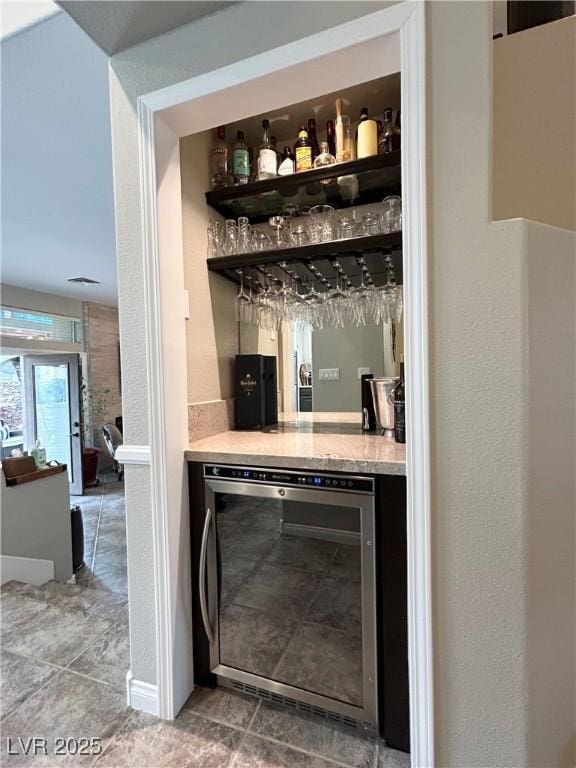 bar with beverage cooler, tile patterned floors, and a bar