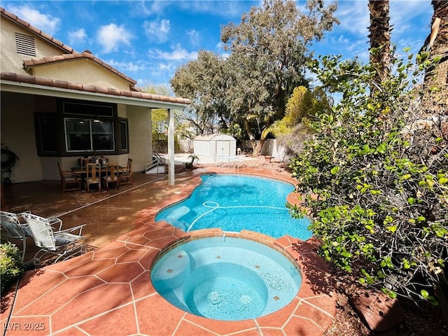 view of pool featuring a patio, a fenced backyard, a storage unit, an outdoor structure, and a pool with connected hot tub